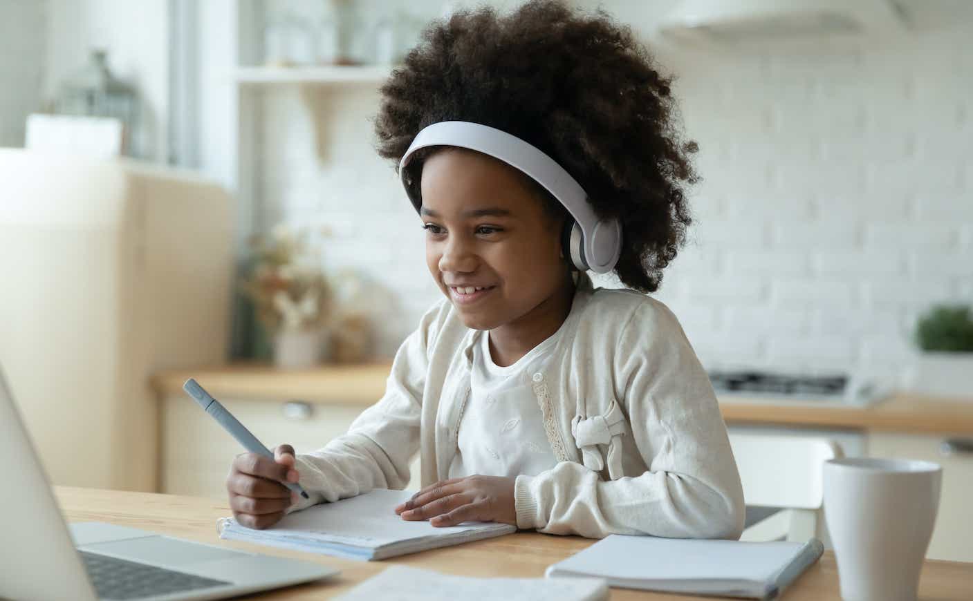 Smiling biracial girl watch video on laptop at home