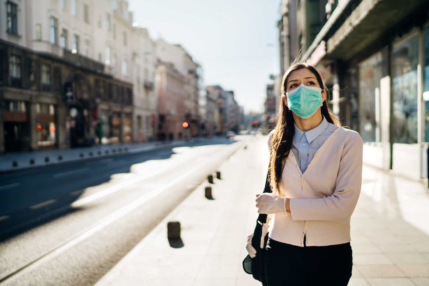 Concerned woman in mask walking through street during coronavirus pandemic