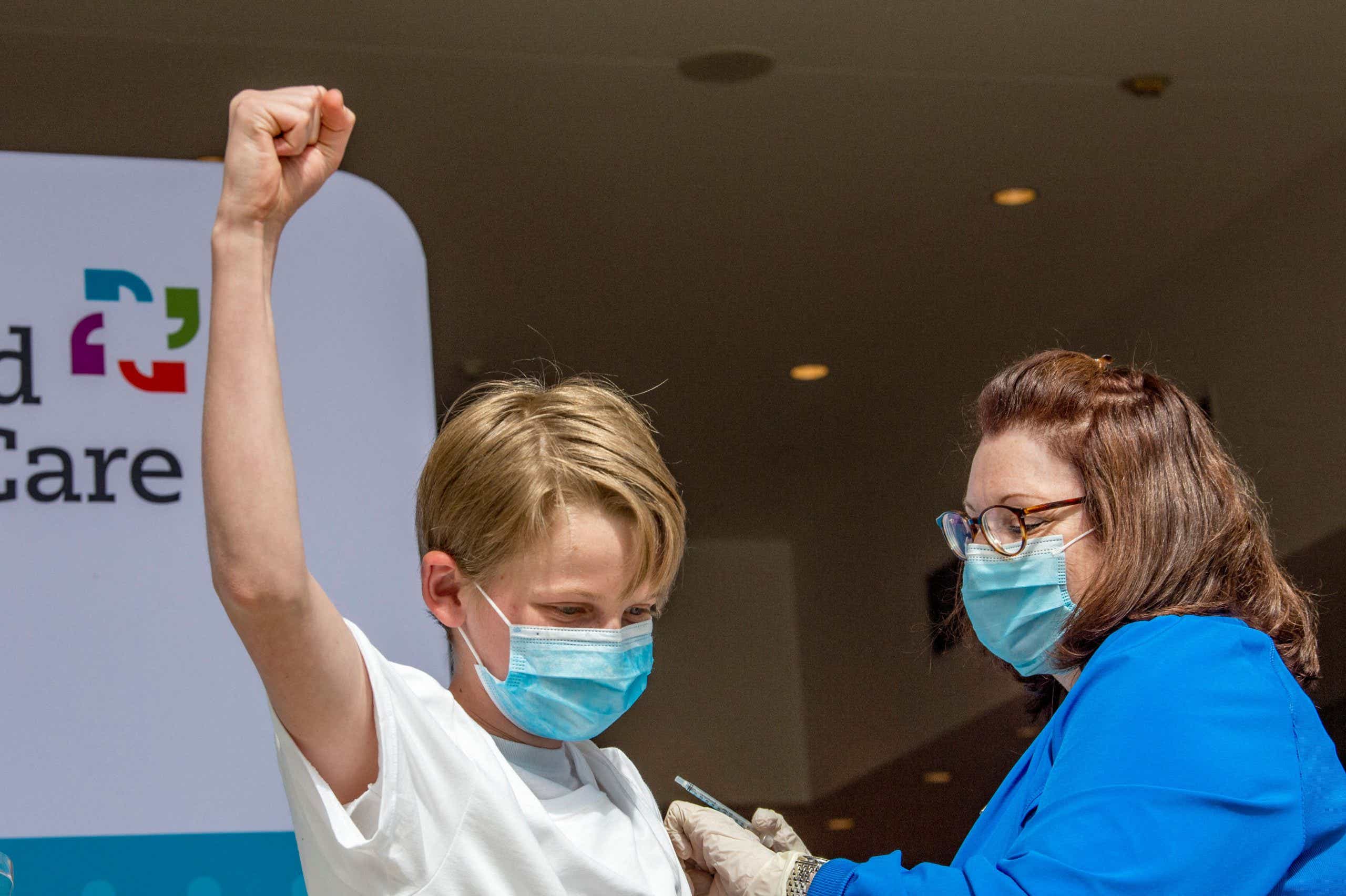 boy raising fist while receiving COCIVD-19 vaccine
