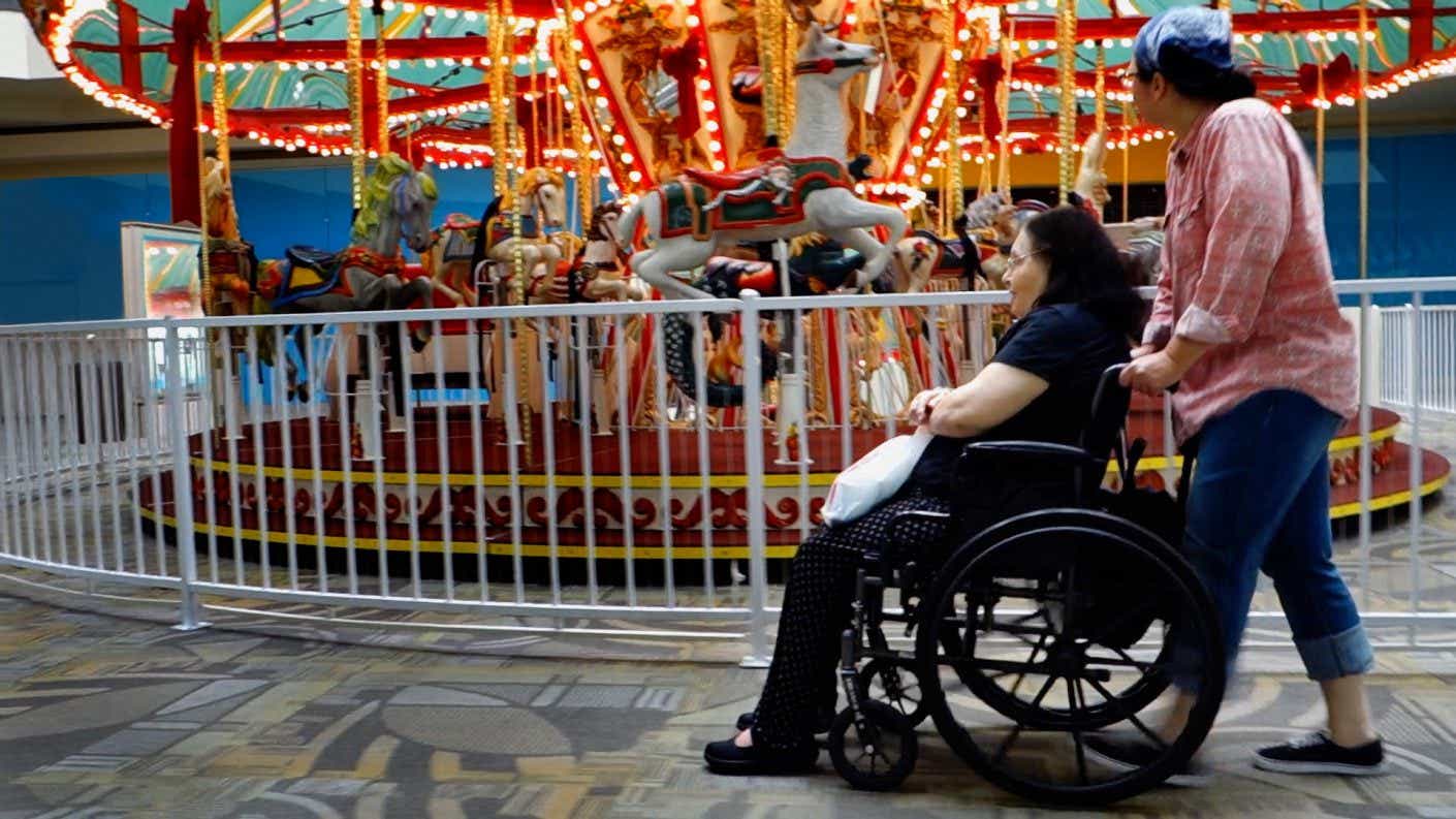 Woman pushes her mother in wheelchair