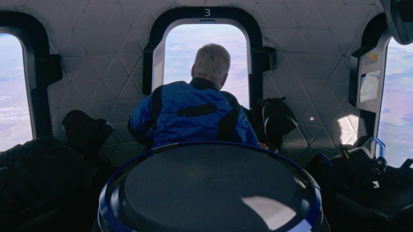 William Shatner looking out the window of the Blue Origin spacecraft.
