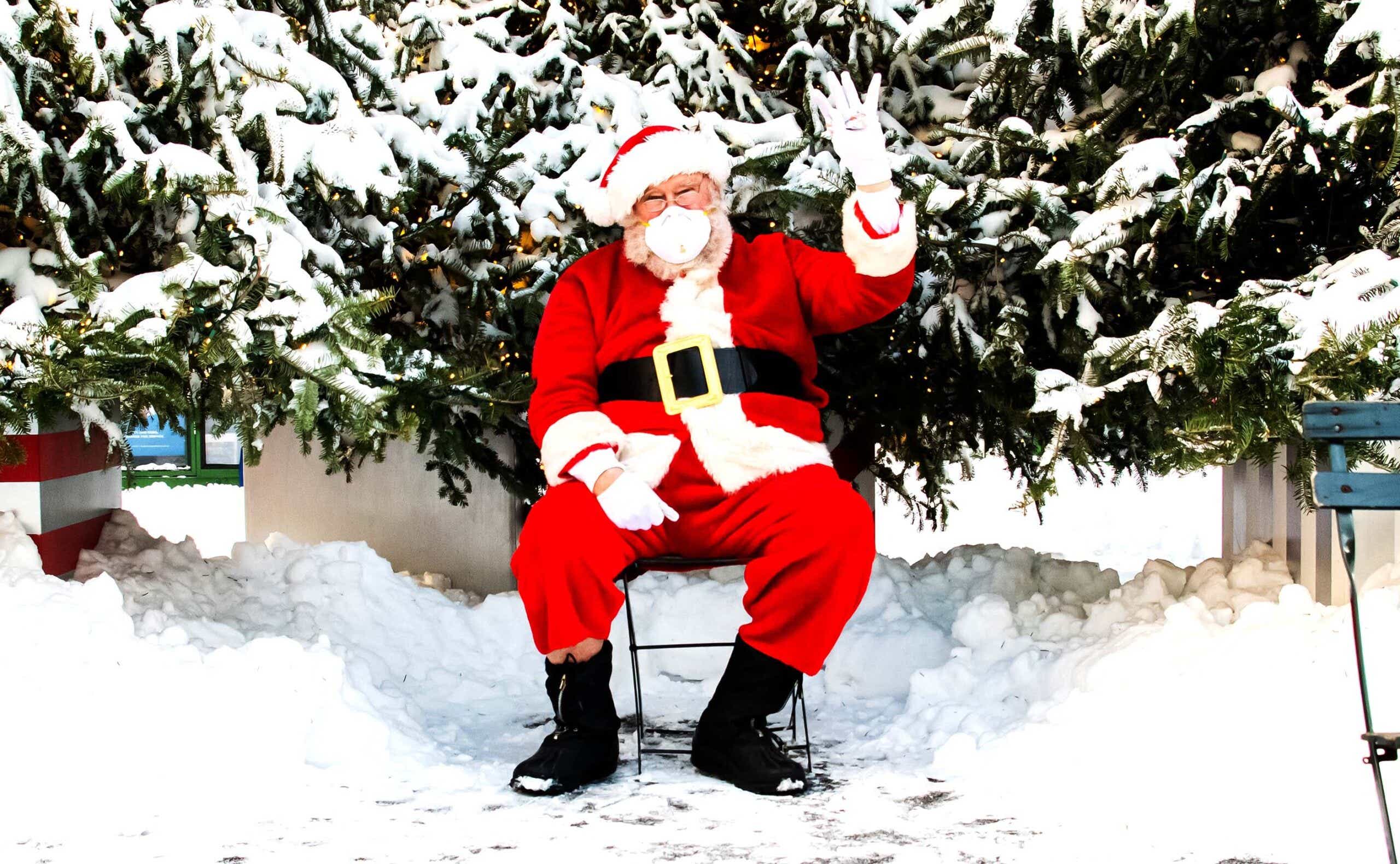 Santa Claus wearing a mask in the snow, giving a peace sign