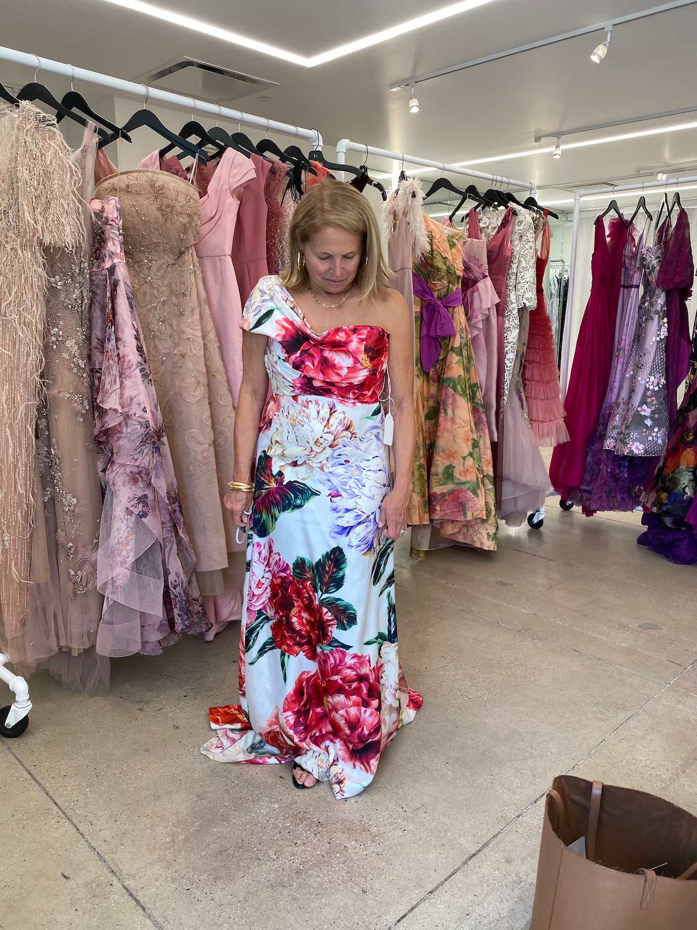 Katie Couric trying on a gown with large pink flowers