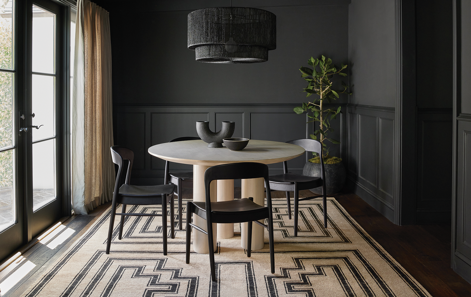 circular table with four chairs around it under black hanging light