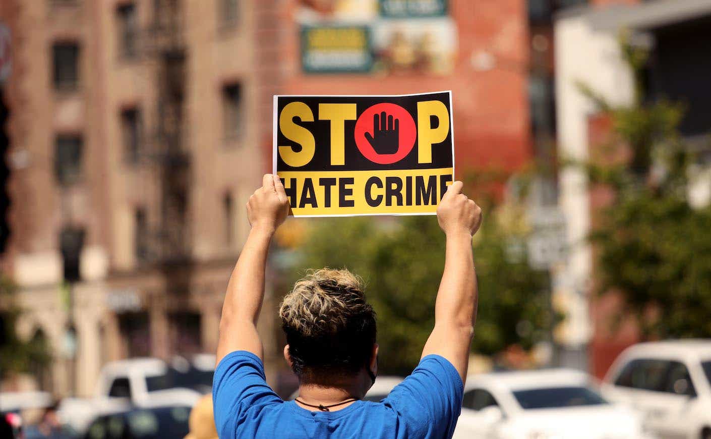photo of a man holding a sign that says stop hate crimes
