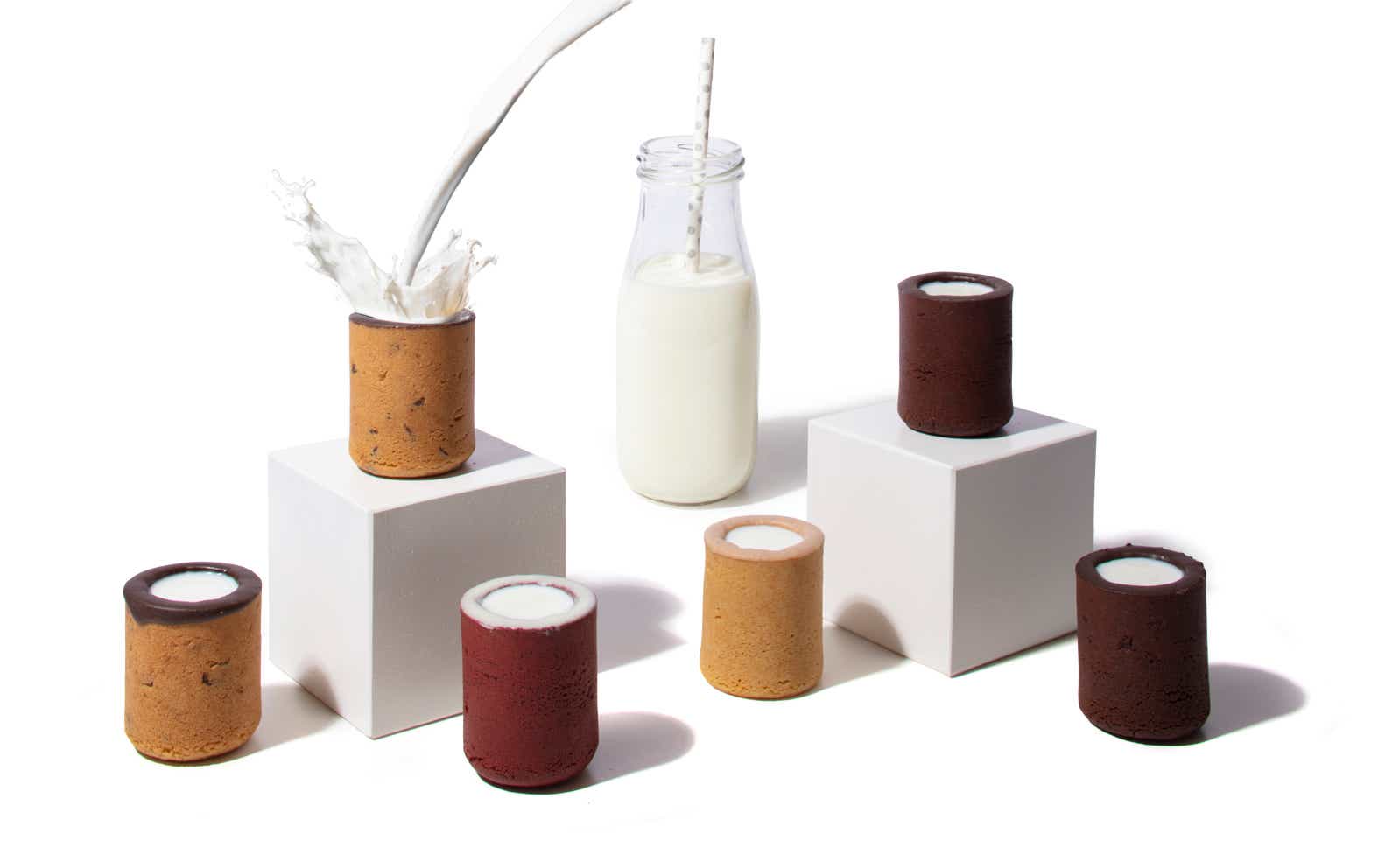 Cookie shot glasses on a white background with a small bottle of milk