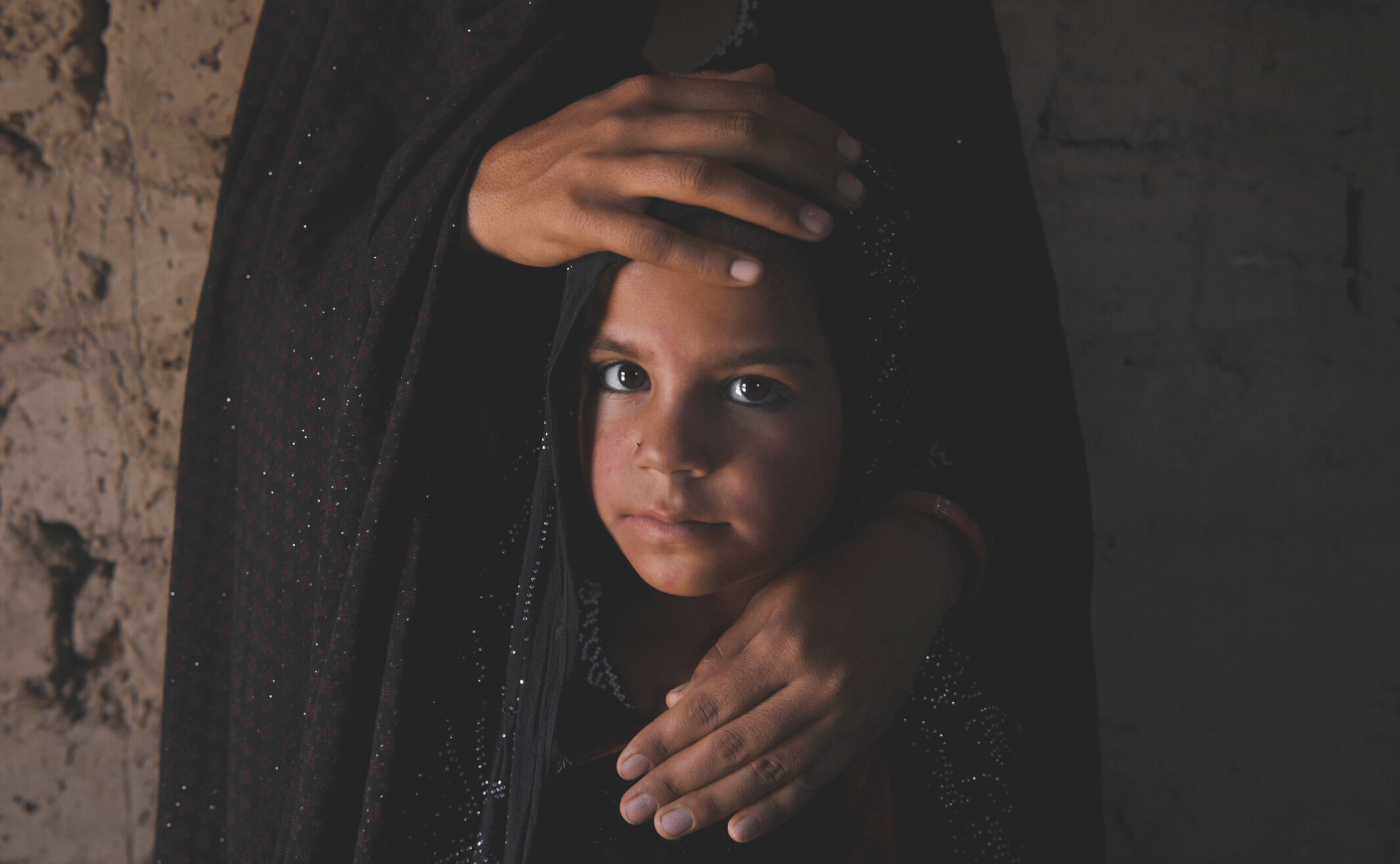 a young girl dressed in black with her mother's hands on her face