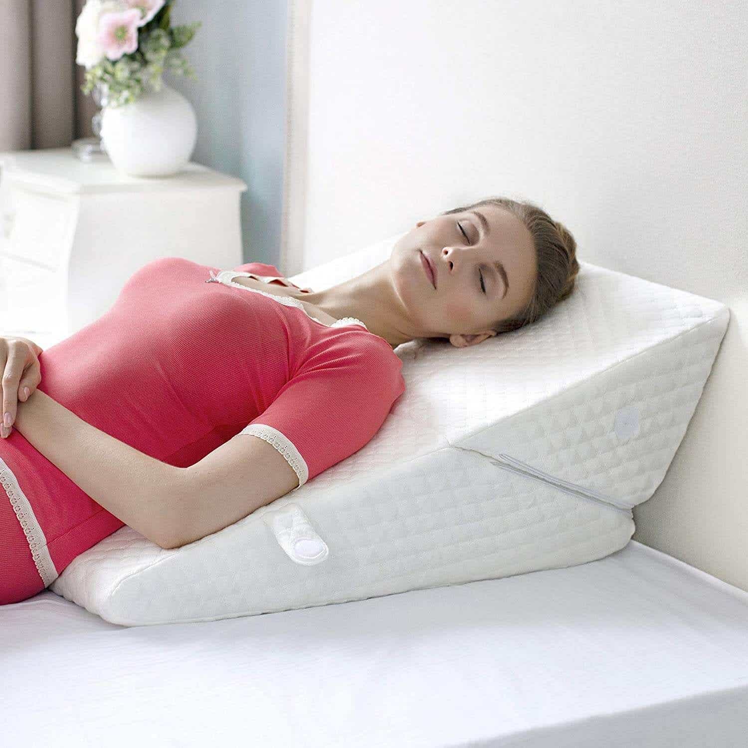 woman in pink top laying on wedge pillow
