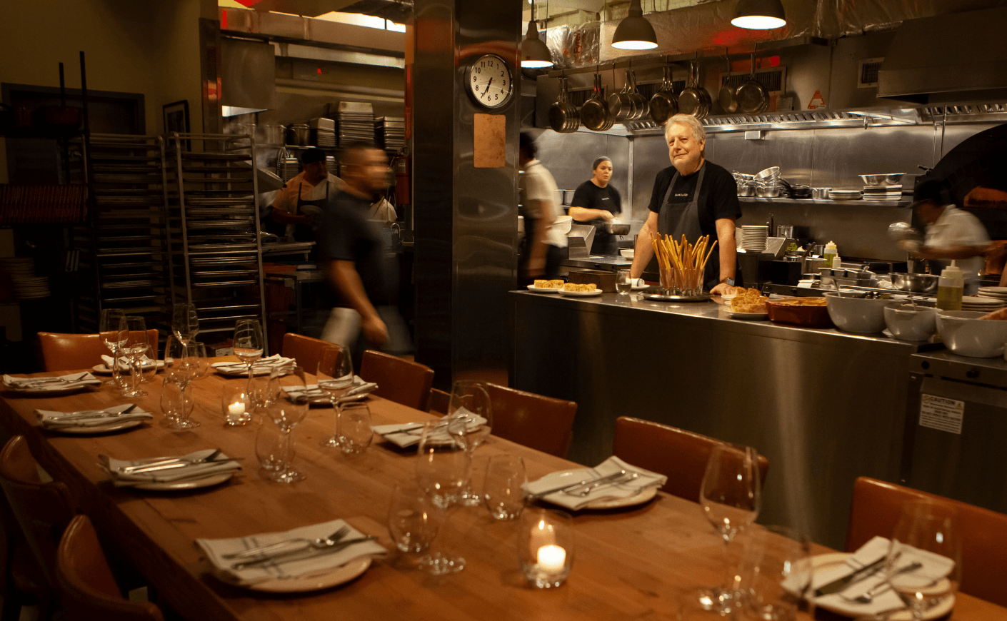 a chef in the kitchen of his restaurant with dining chairs