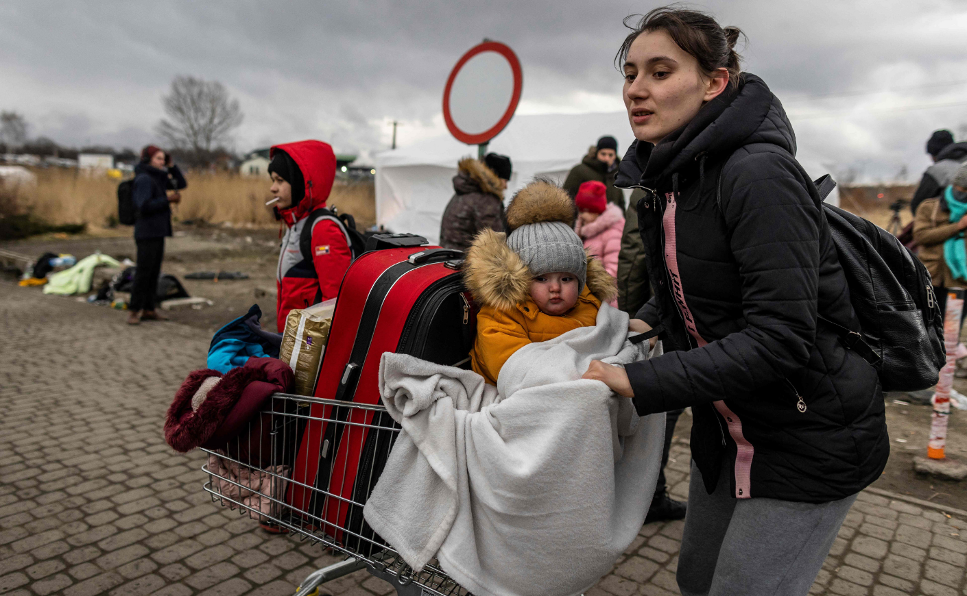 woman and baby fleeing Ukraine with bags