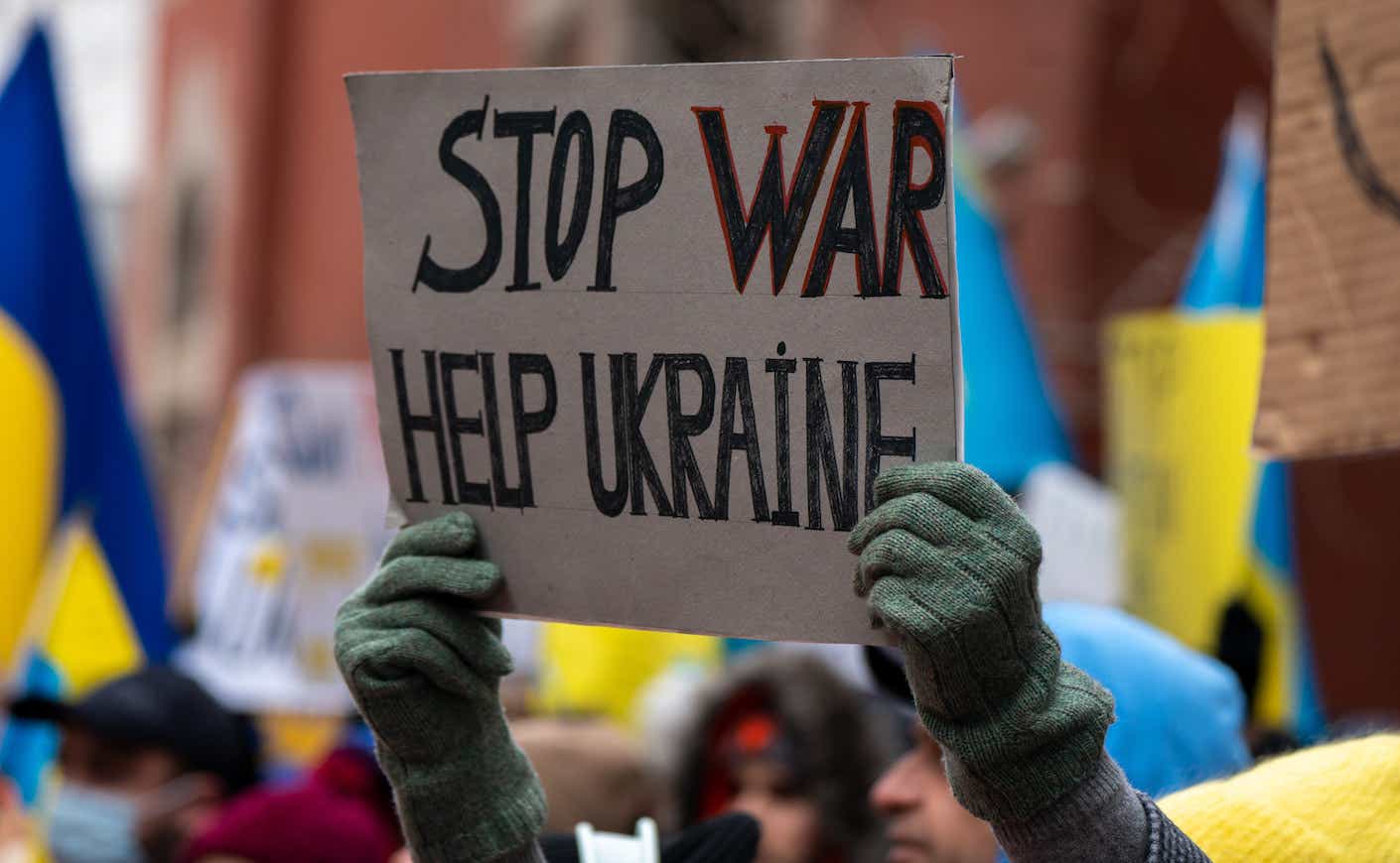 protestor holding up a sign that says "stop war help ukraine