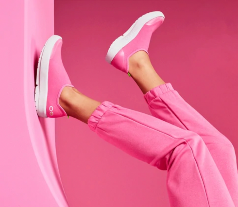 legs in pink joggers with their feet on the wall wearing pink shoes