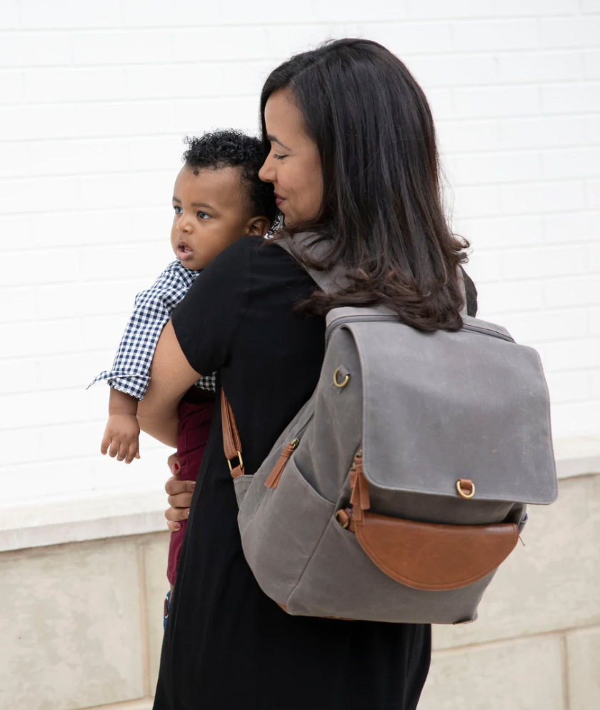 woman wearing Momkindness backpack and carrying a child