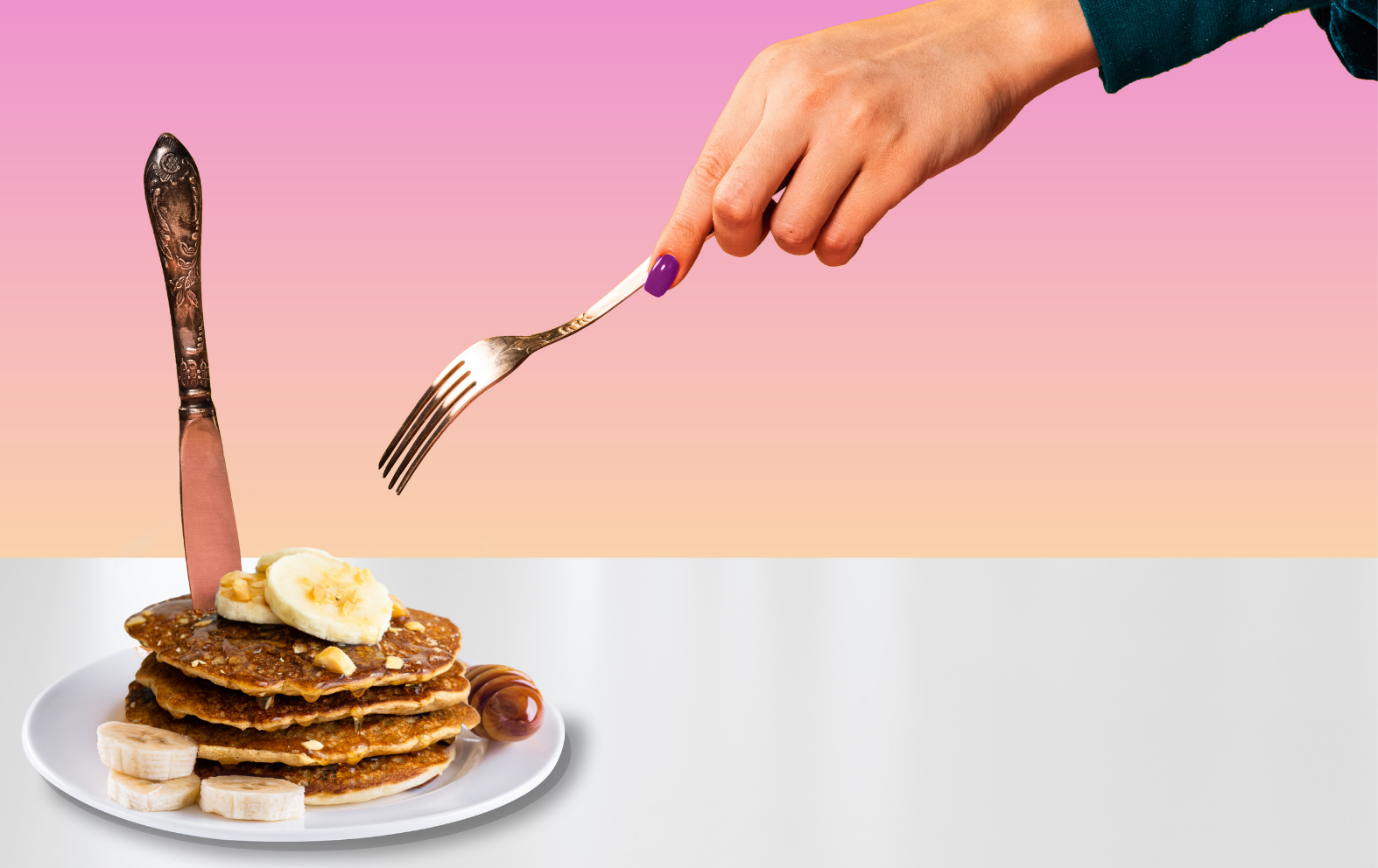 Hand with fork reaching for plate of pancakes