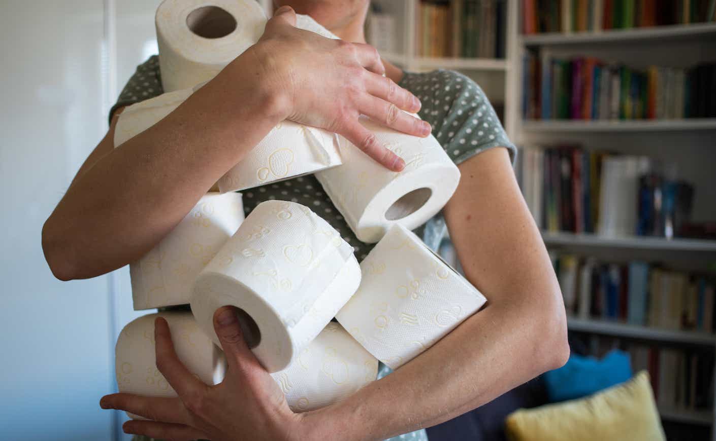 woman holding multiple rolls of toilet paper