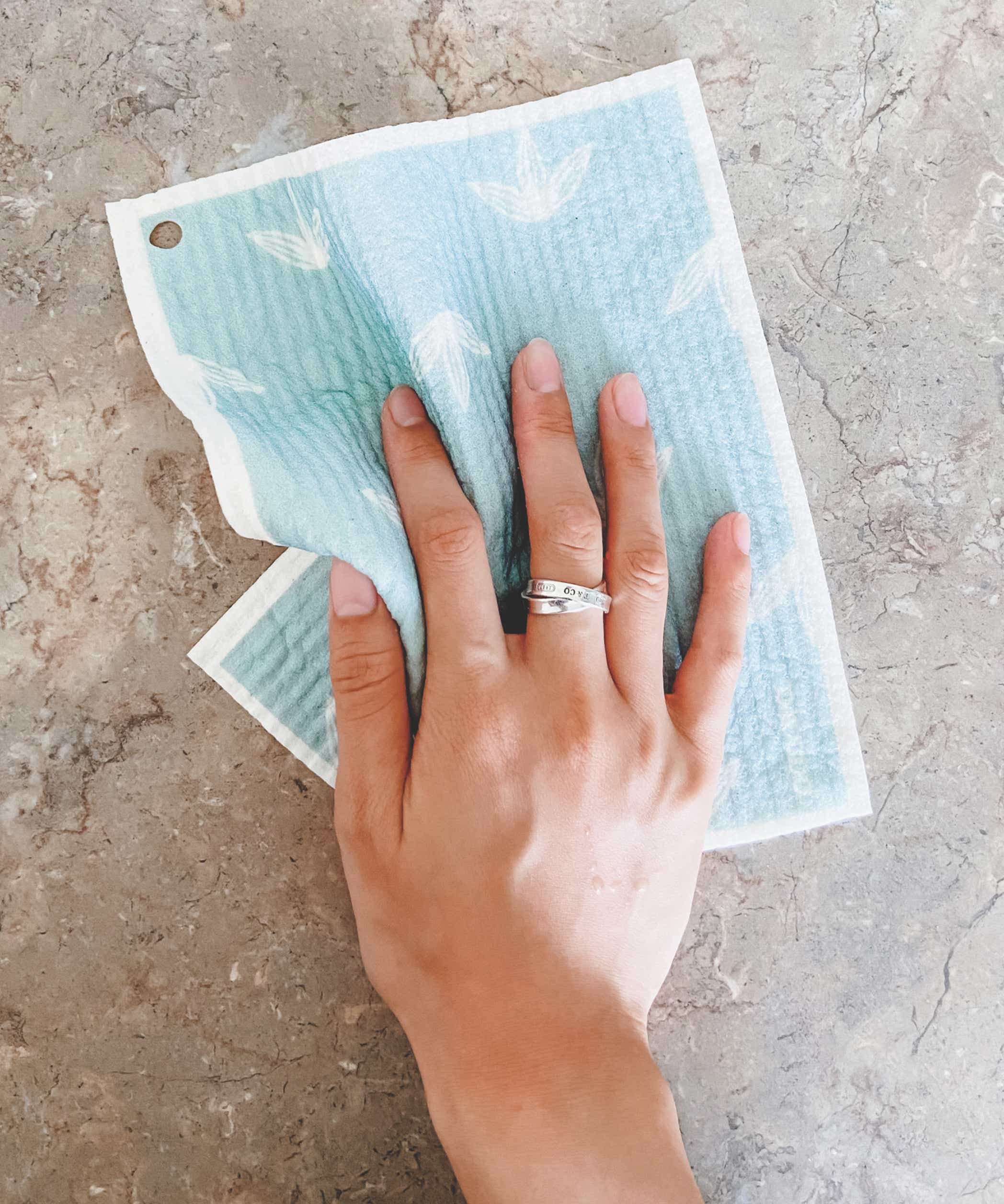 hand wiping a surface with a papaya reusable paper towel