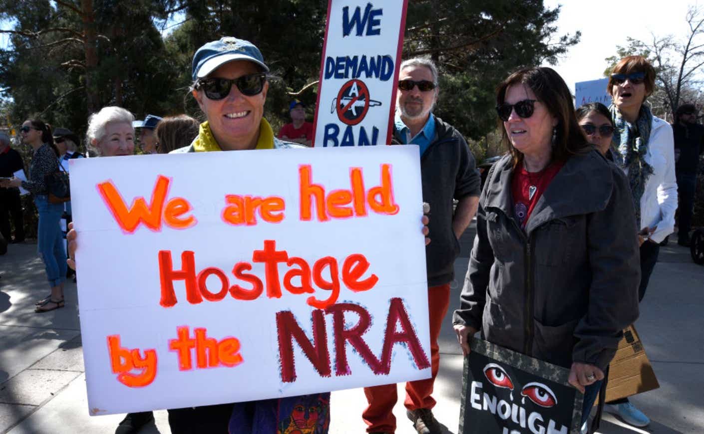 A protestor holds a sign saying "We are held hostage by the NRA"