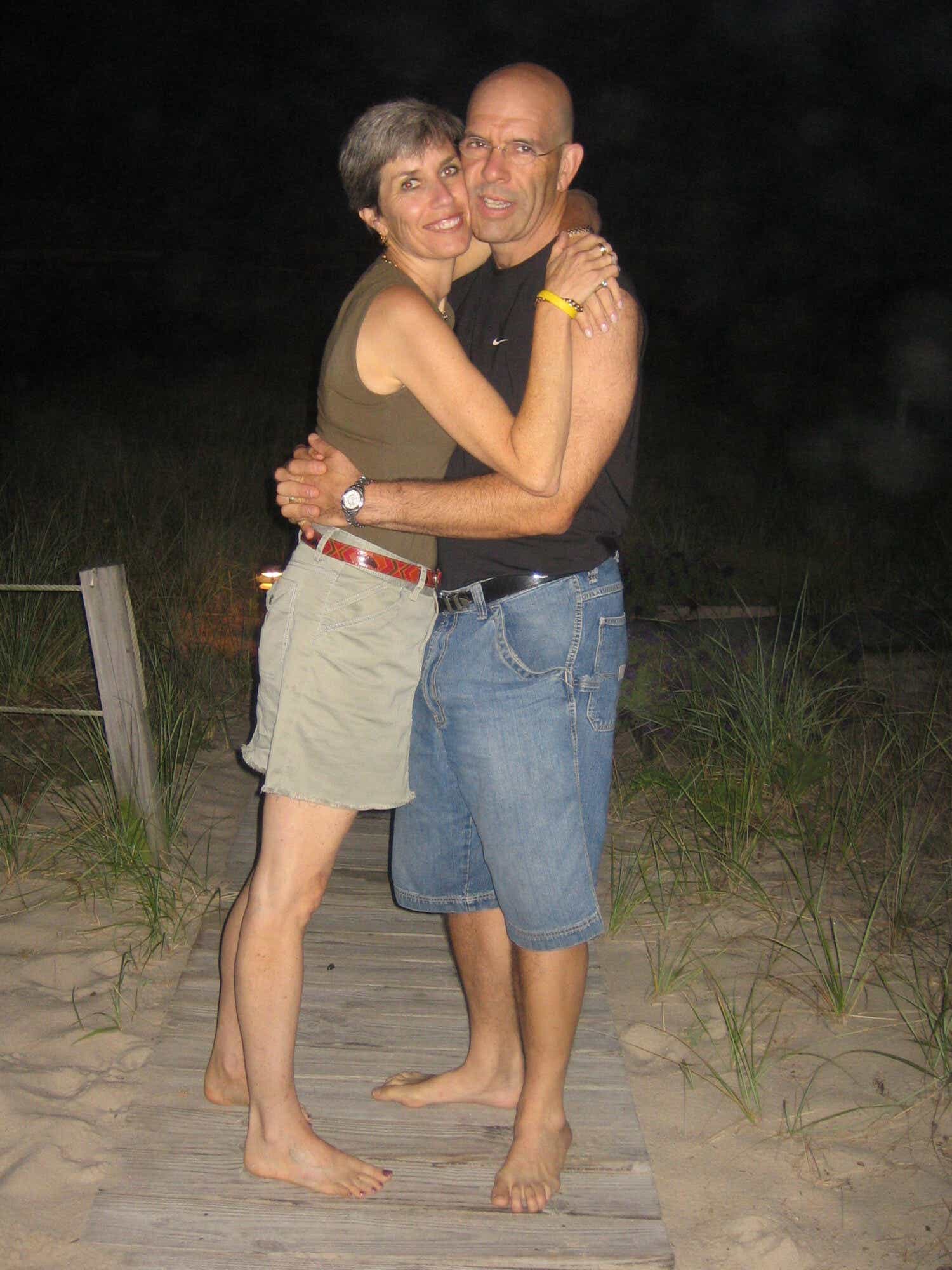 Janice and Ian hug on a beach at night