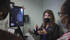Woman in mask shows mammogram screen