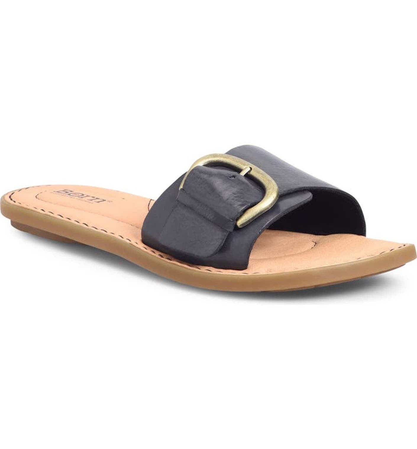 A flat, brown sandal with a buckled, black leather strap.