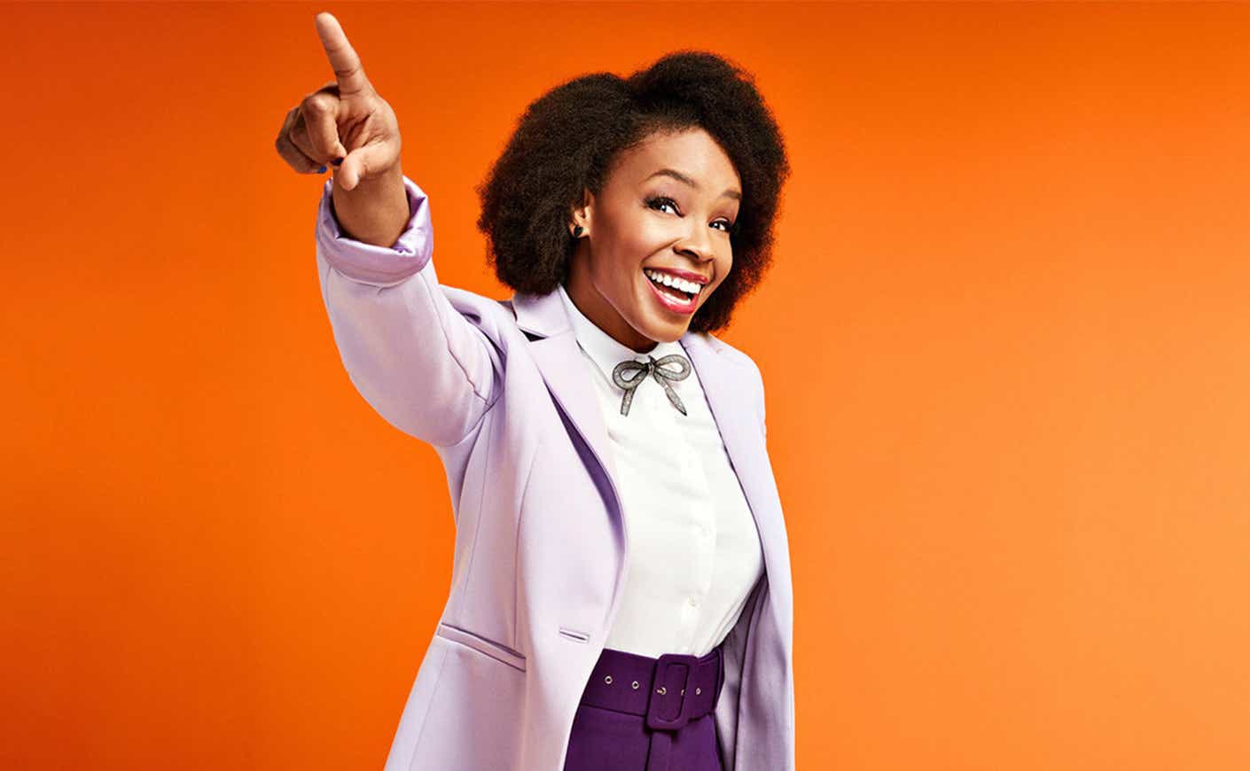 Amber Ruffin points and smiles on orange background