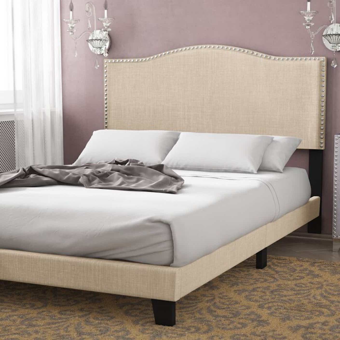 A cream-colored, upholstered bed pictured in a bedroom.