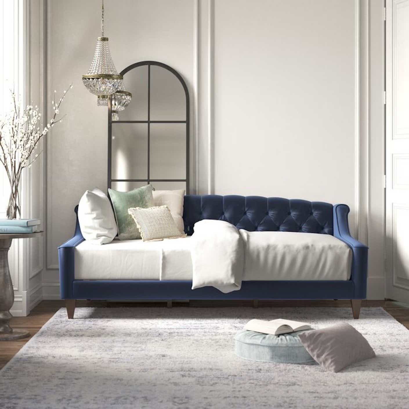 A dark blue, velvet daybed with tufted details in a sunny living space.