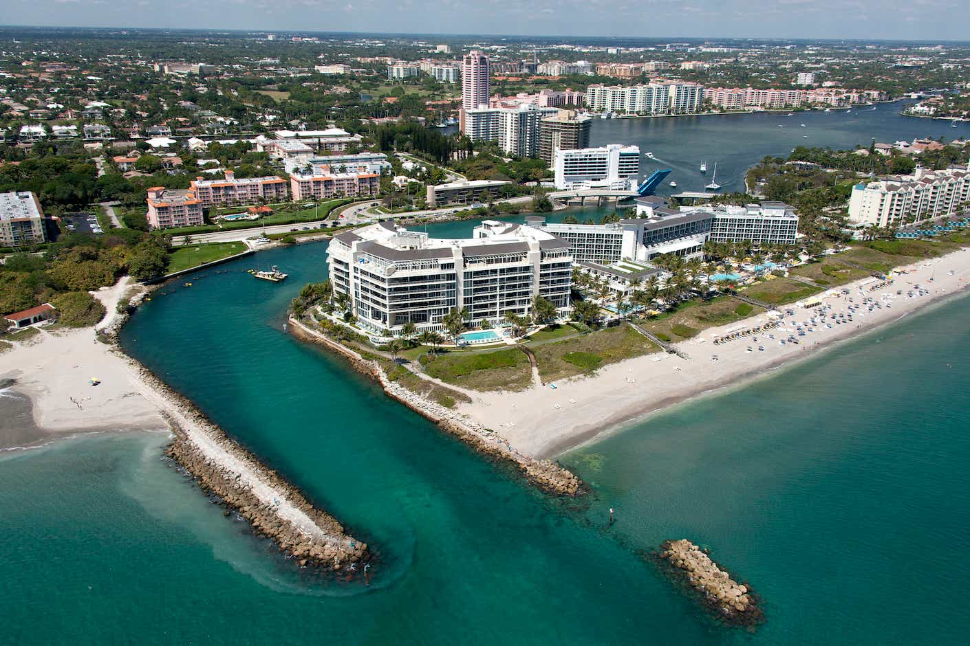 An aerial photo of Boca Raton, including a deep blue inlet and white beach. 