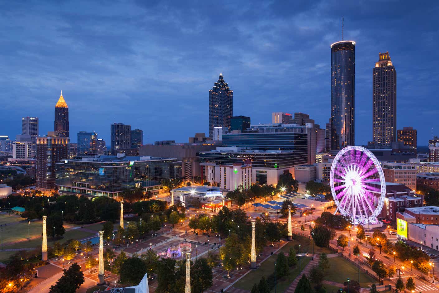 An elevated city view of Atlanta with a lit-up ferris wheel at dusk.