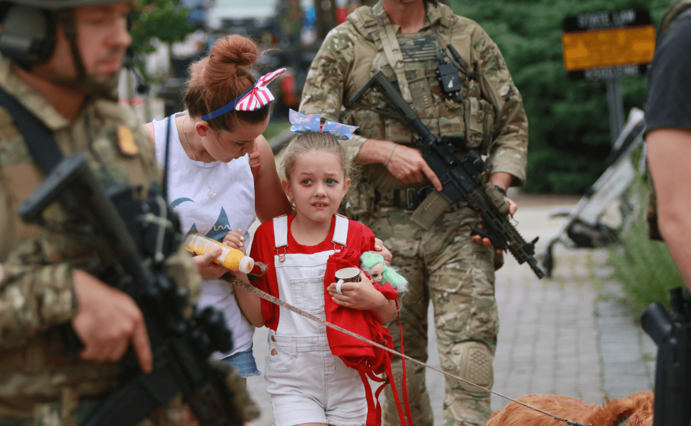 a scared little girl surrounded by military with guns