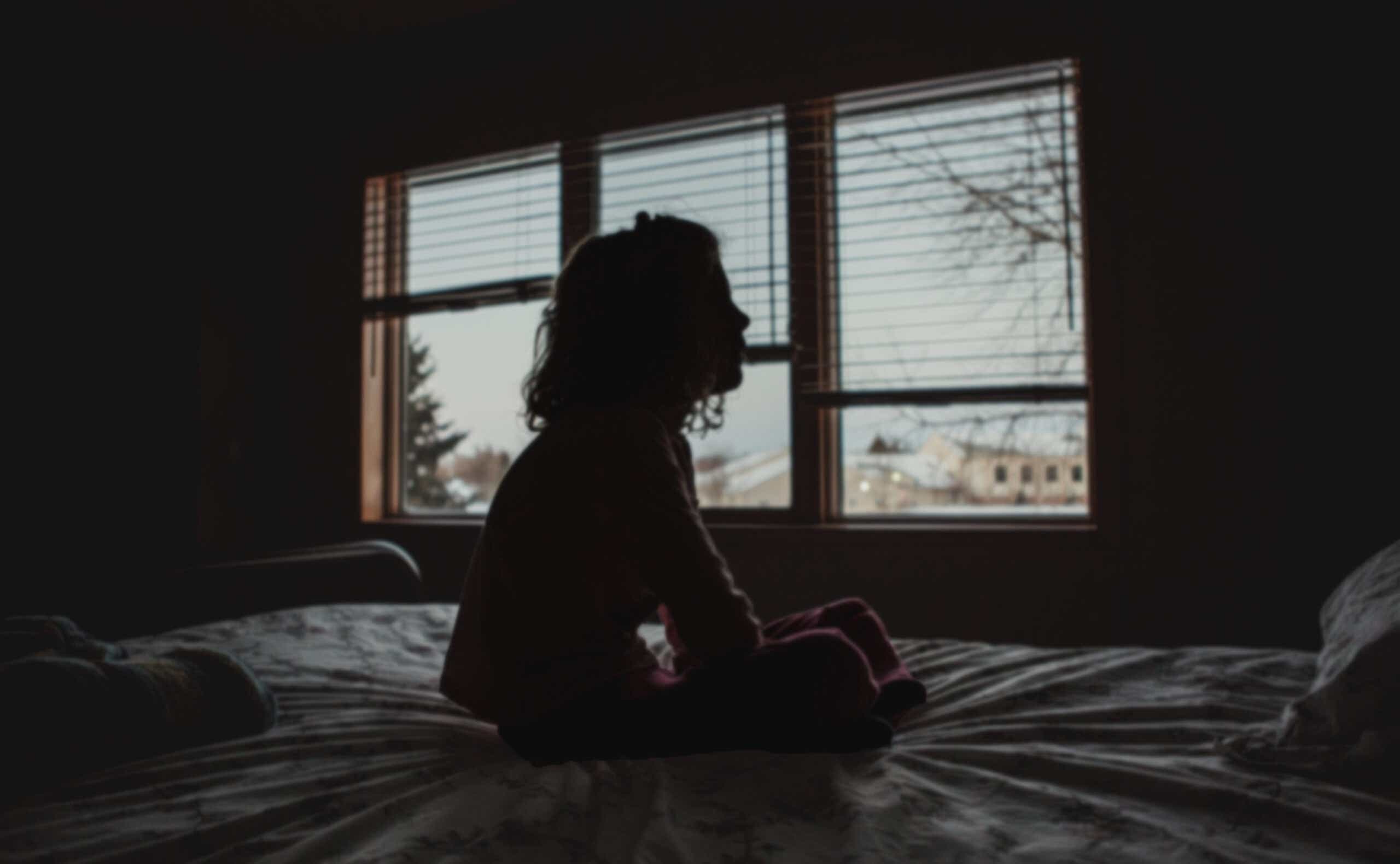 Silhouette of a young girl sitting in a bedroom