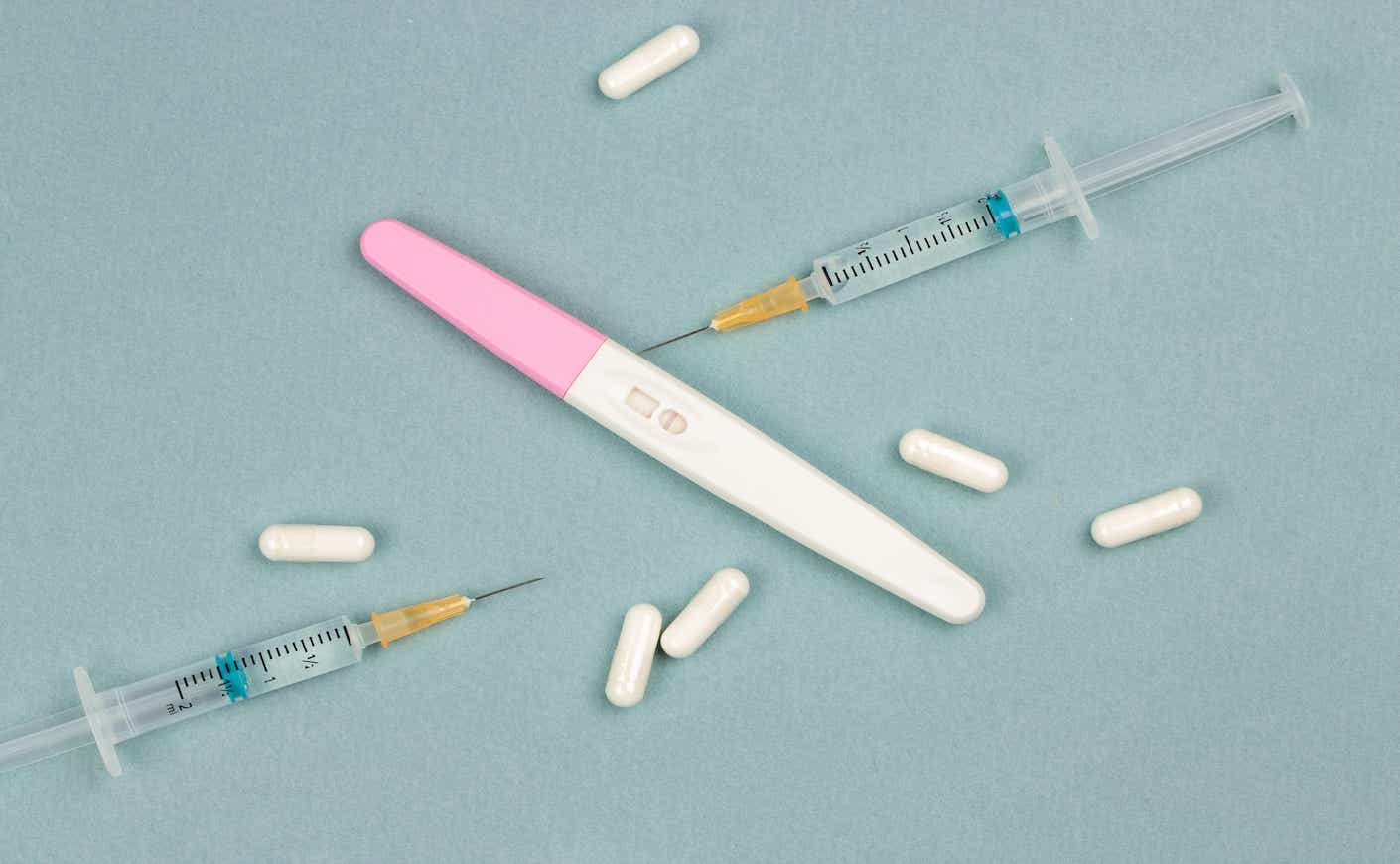 a negative pregnancy test with needles and pills around it