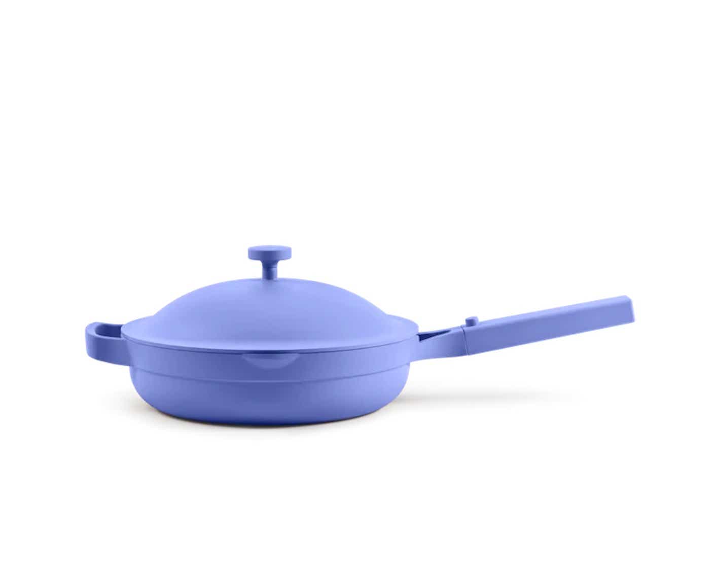 A bright blue nonstick lidded pan with a long handle pictured in front of a blue background.