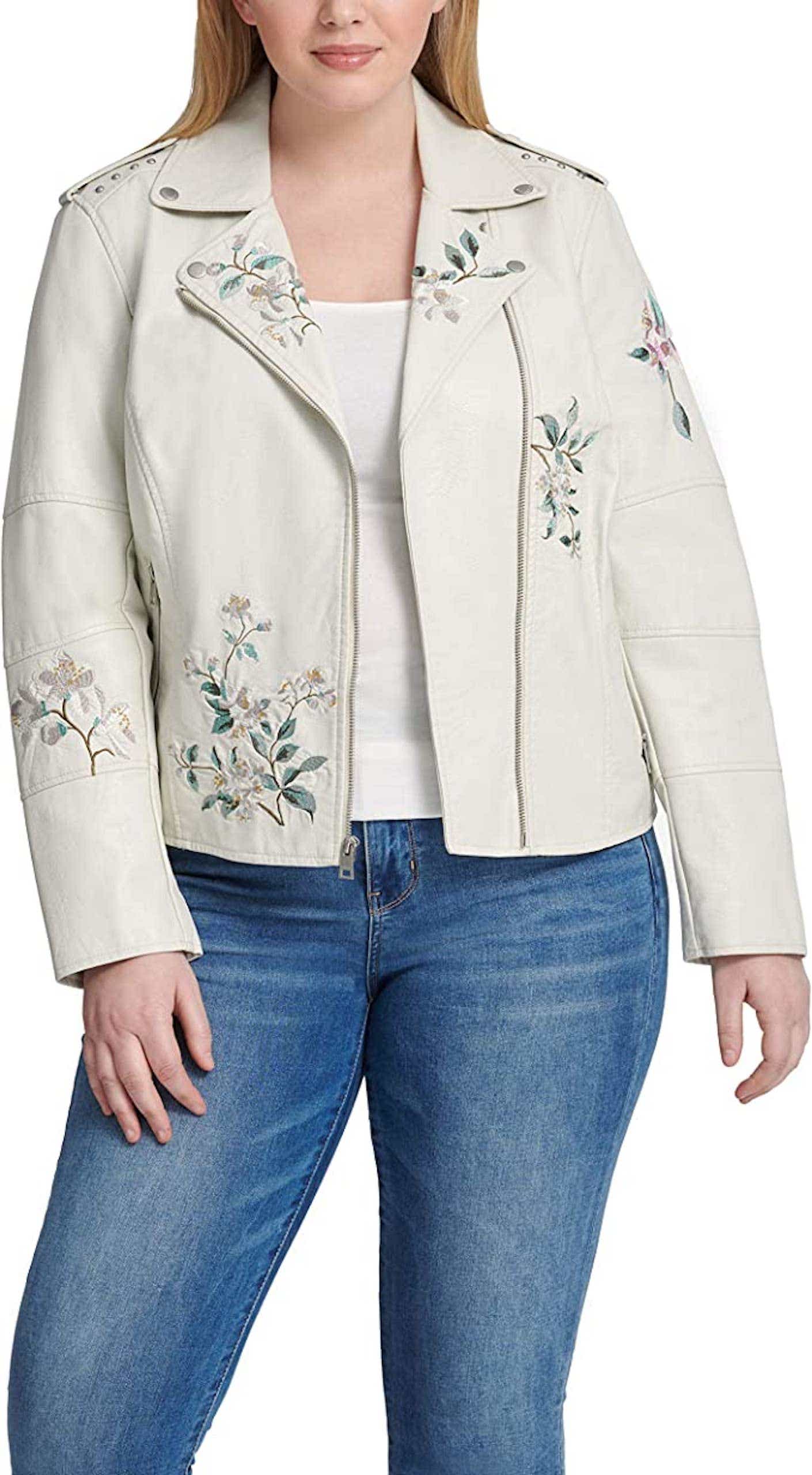 A woman wears a light beige leather jacket covered with white and green floral embroidery.