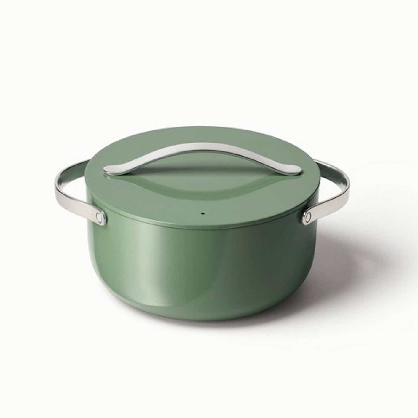 A sage green dutch oven with metal handles is pictured in front of a white background.