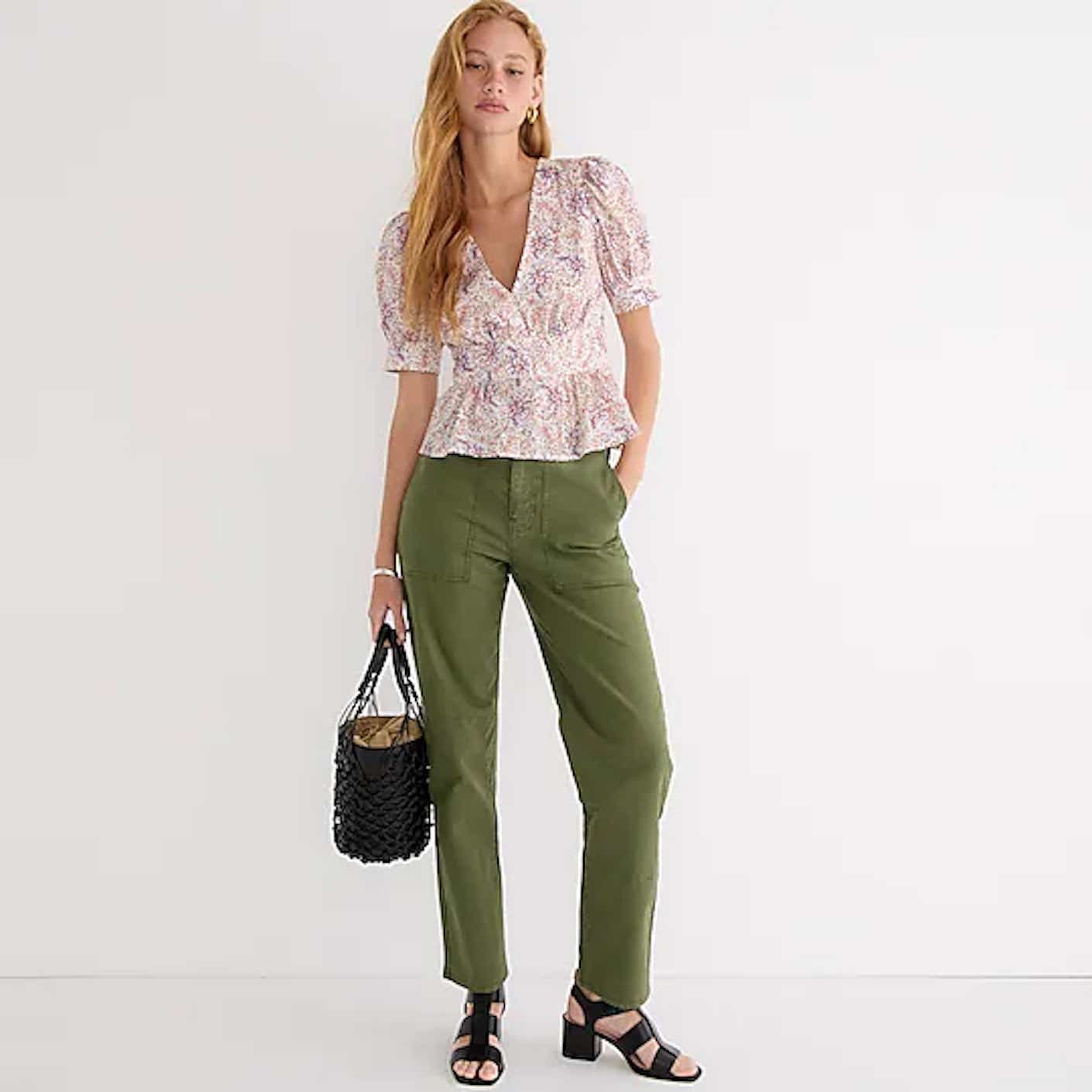 A woman wears army green, twill, straight-legged cargo pants with deep pockets.