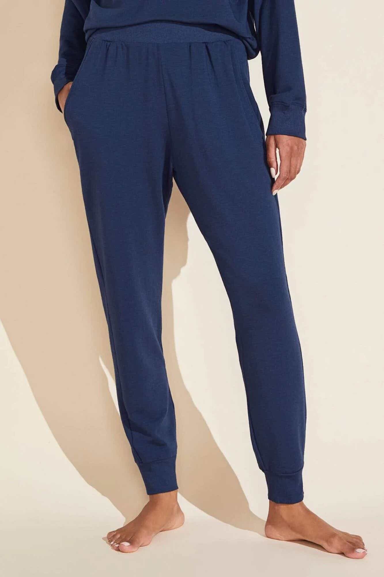The lower half of a person wearing soft, dark blue, knit lounge pants that are fitted at the hem.