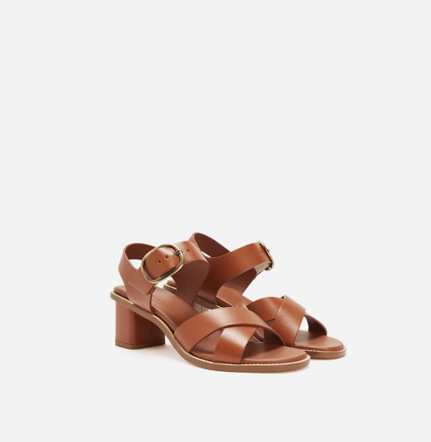 A strappy pair of chesnut brown heeled shoes are pictured in front of a white background.