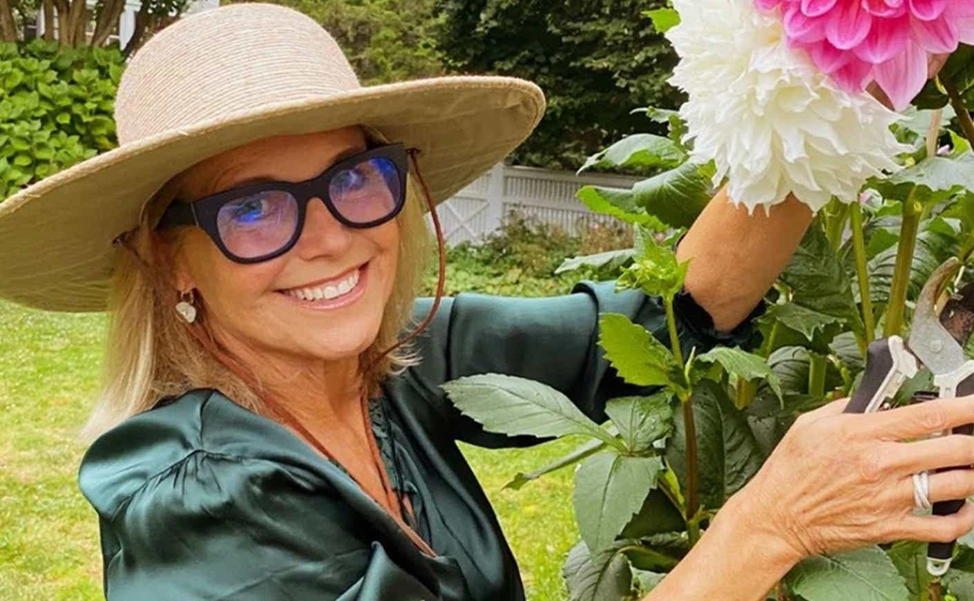 Katie Couric tending to pink and white flowers in her garden