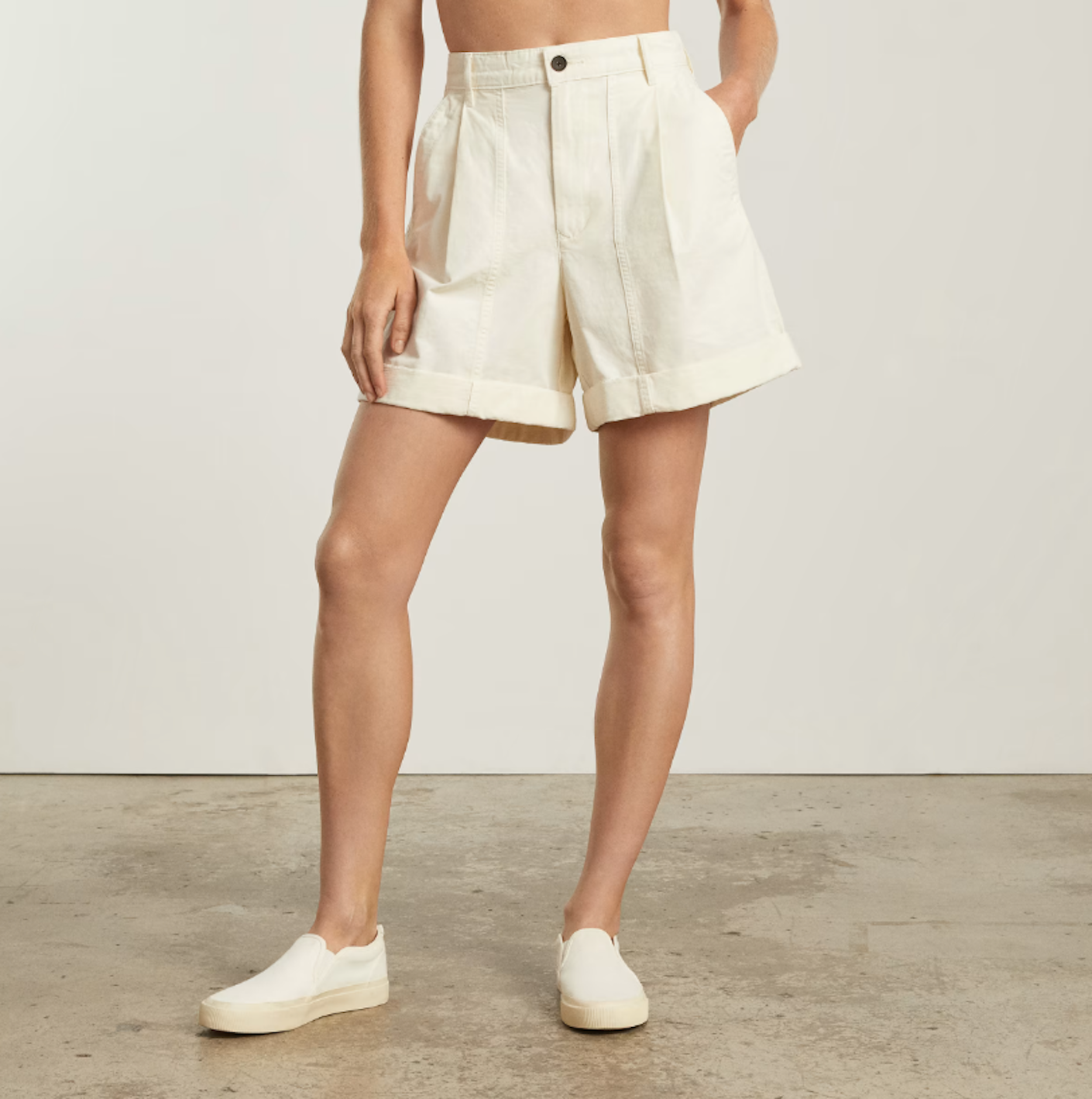 a person poses in structured cream mid-length shorts.