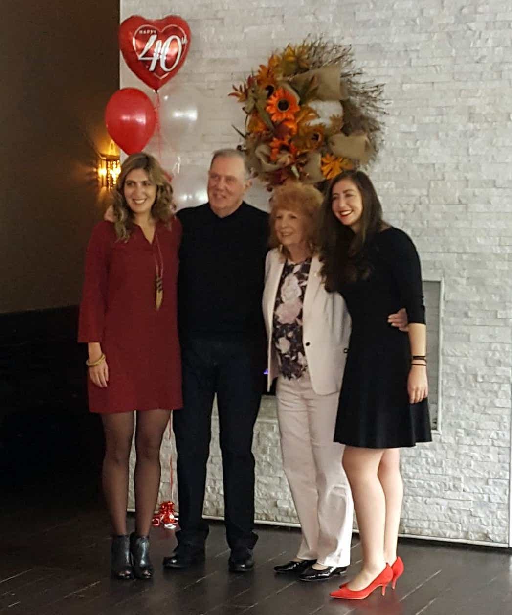 Lawrence Caruso poses and his wife and two daughters with a 40th anniversary balloon behind them