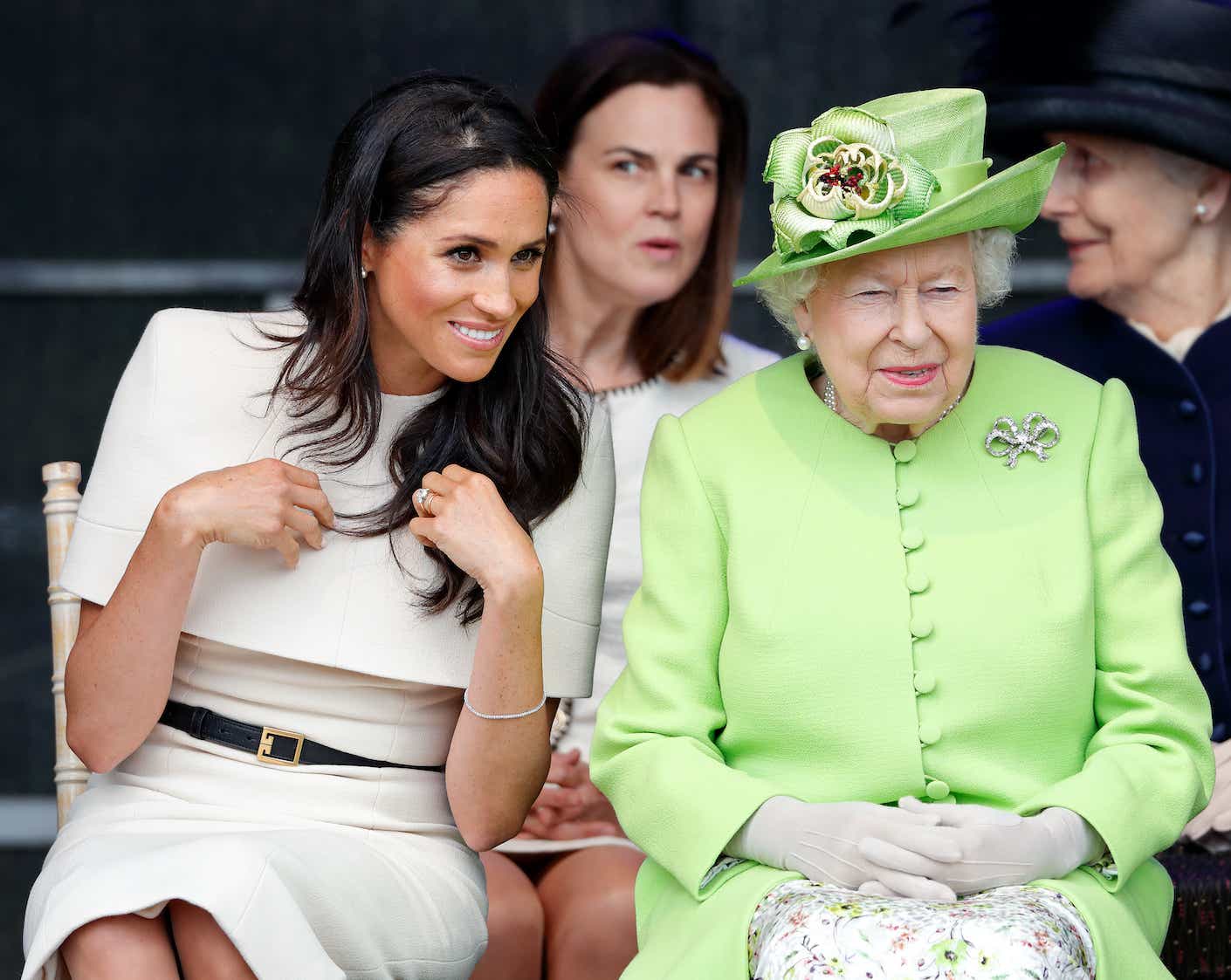 Meghan, Duchess of Sussex and Queen Elizabeth II attend a ceremony to open the new Mersey Gateway Bridge in 2018. The queen wears a bright green suit.