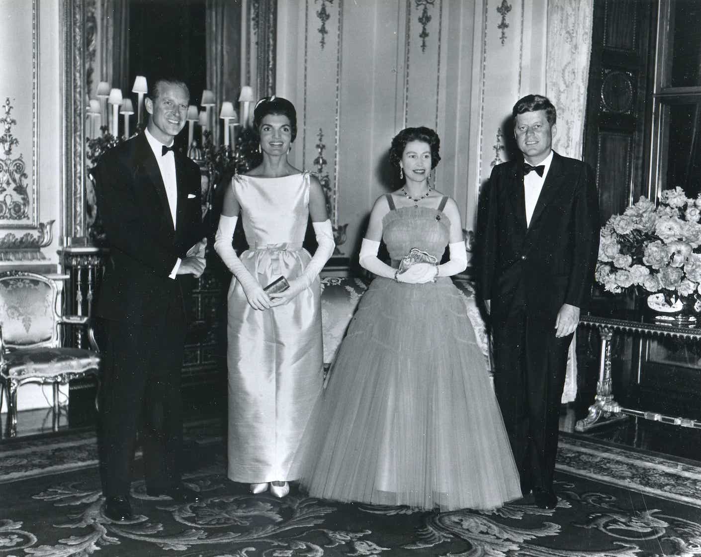 President and Mrs. Kennedy pose with Queen Elizabeth and Prince Philip before the Queen's dinner honoring the Kennedys at Buckingham Palace during the President's 1961 visit. All wear formal dress.