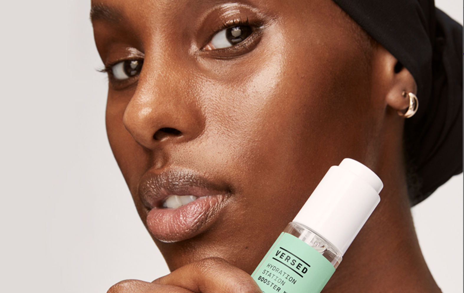 Woman holding Versed skincare product against her face