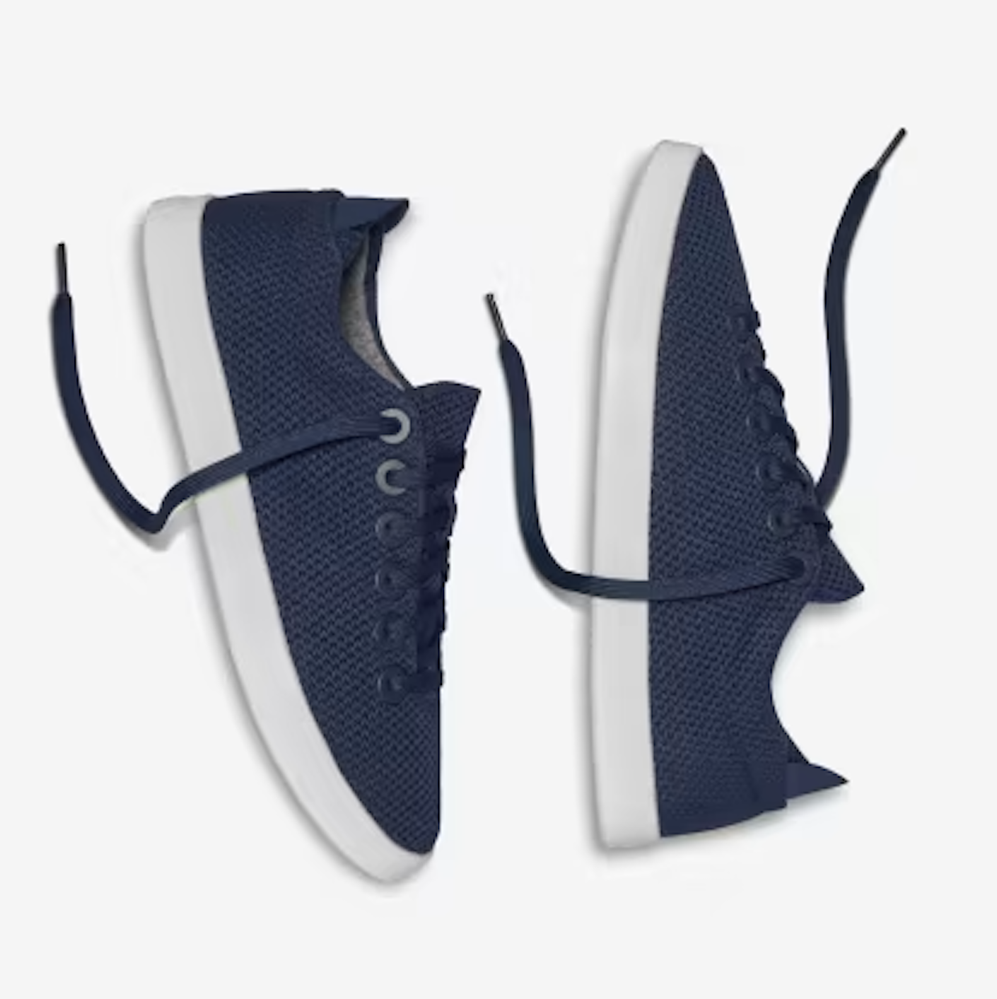 A pair of navy blue lace-up tennis shoes with white soles sit side by side in front of a white background.