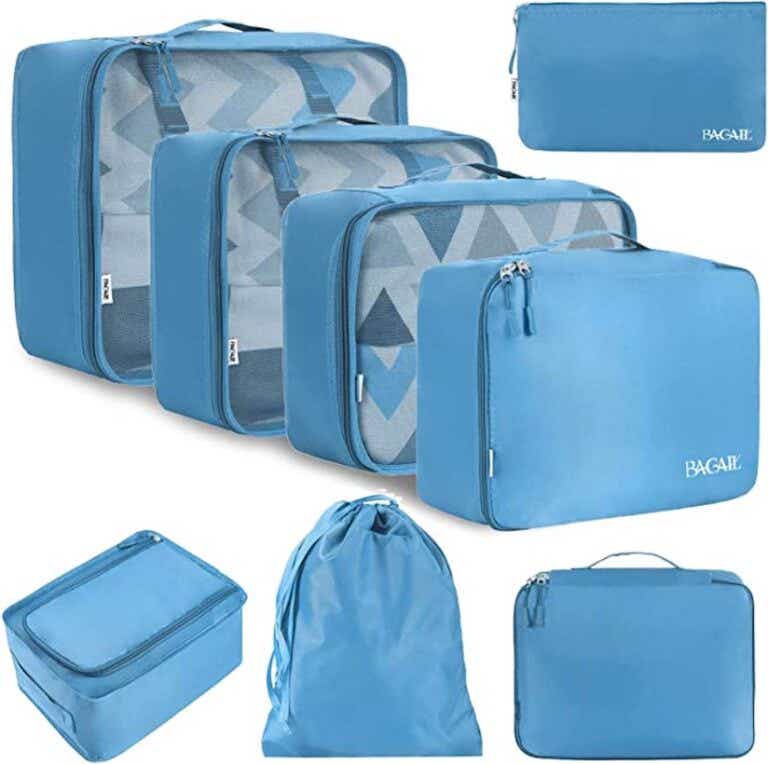 A stack of differently sized blue zip up packing cubes pictured in front of a white background.