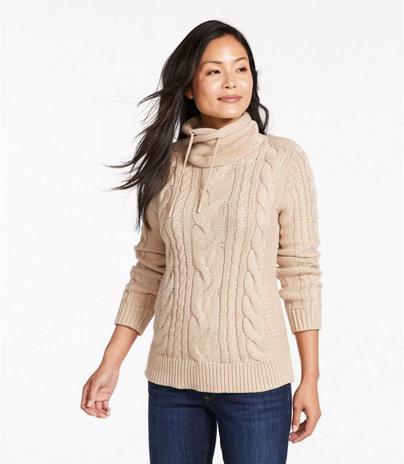 A woman wears a pull over sweater with an drawstring-adjustable turtleneck that is hip-length and beige.