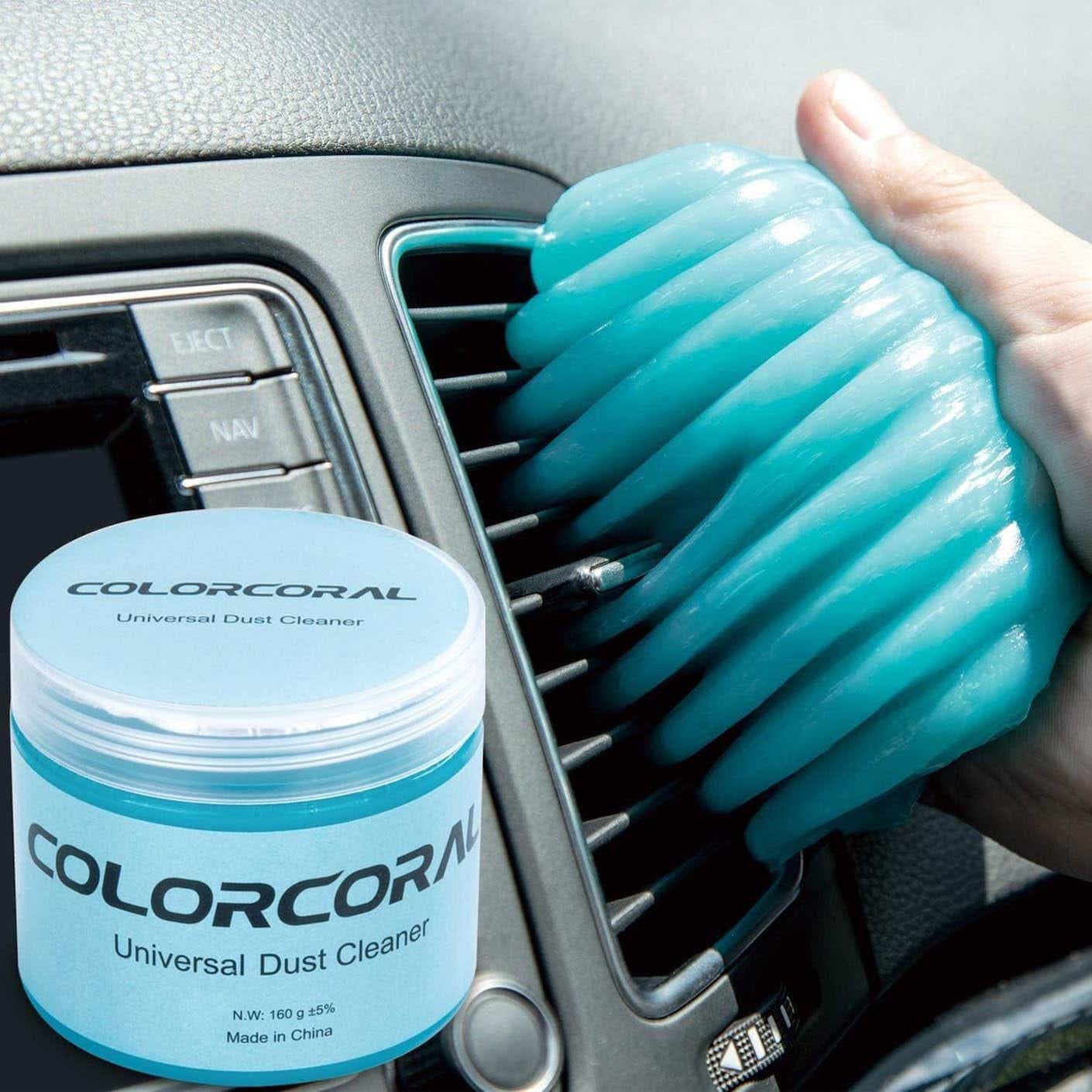 A hand uses blue cleaning gel to clean out the air vents in a car.