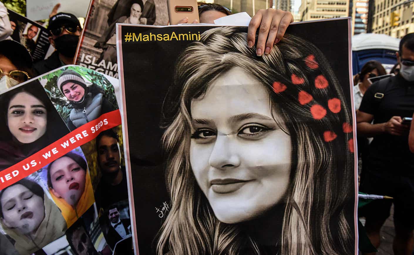 protestors in Iran hold a sign of Mahsa Amini