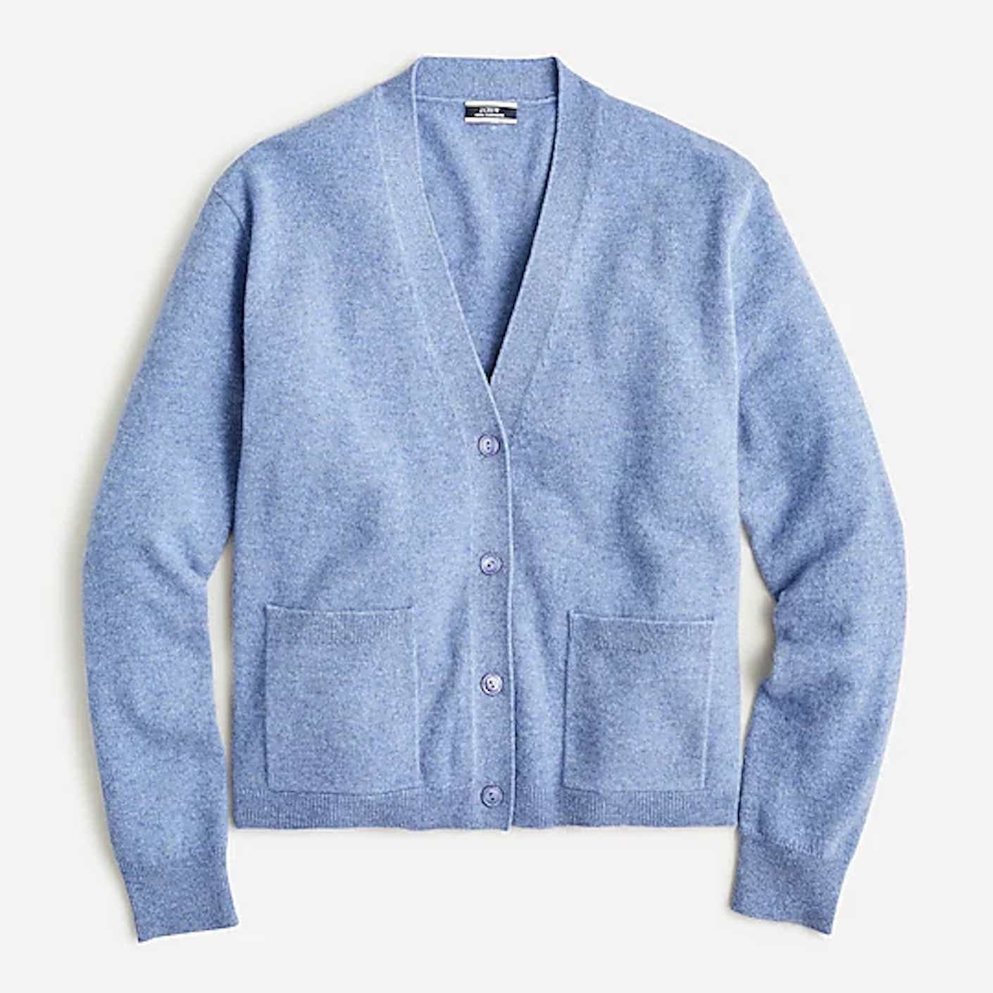 A fitted, button down, hip length blue cardigan with long sleeves lies flat.
